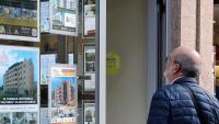 Un home observa l'aparador d'una agència immobiliària, a Astúries