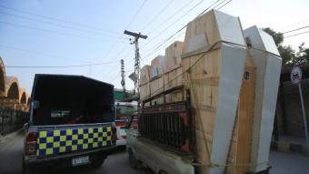 Una camioneta transporta taüts al lloc dels atemptats, a Peshawar