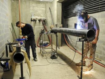Uns operaris treballant a la sala on s’instal·larà la caldera de biomassa que alimentarà diversos equipaments Ramon Ferrandis