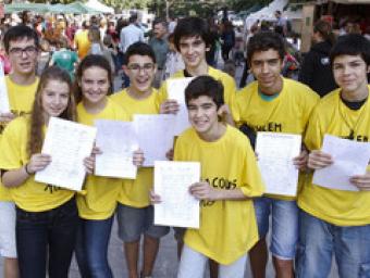 Un grup d’alumnes de l’institut vestits amb samarretes grogues mostren algunes de les firmes recollides Griselda Escrigas