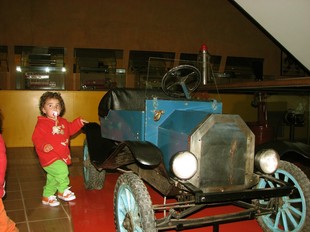 Un nen davant d'un dels vehicles més antics que hi ha al museu.