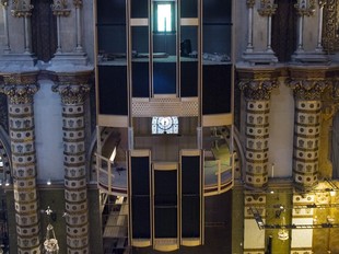 Dalt, vista frontal de l'estructura de fusta de l'orgue, que s'ha instal·lat en una nau lateral a tocar del presbiteri, com es pot veure en la fotografia inferior.  GABRIEL MASSANA