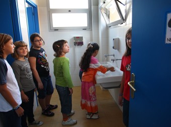 A l'esquerra, un grup d'alumnes de l'escola Baldiri Reixac de Banyoles rentant-se les mans. A la dreta, el SES de Sils amb els ordinadors nous. LL. SERRAT