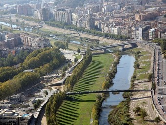 El riu Segre al seu per Lleida. A baix, una embarcació de neteja i un home pescant a la riba.  EL PUNT / ELENA VALLÉS / ACN