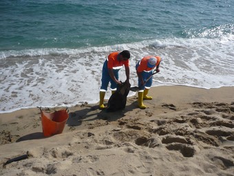 Els operaris municipals netegen les taques de gasoil a la platja del Varador de Mataró./  LL.M