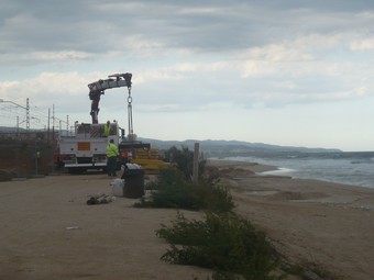 Les màquines reforçant ahir l'escullera de roques que protegeix la via del tren i el port de Mataró al fons.  E. FERRAN