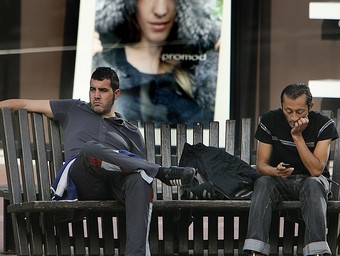 Dos homes amb màniga curta ahir a Girona, davant un anunci de roba d'hivern.  MANEL LLADÓ