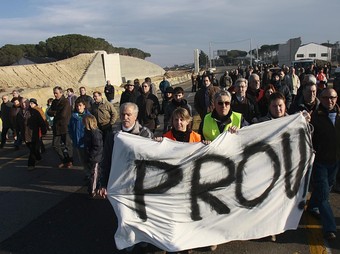 Els manifestants amb la pancarta en el moment de tallar la carretera N-II. A l'esquerra, les obres aturades./  CLICKART FOTO