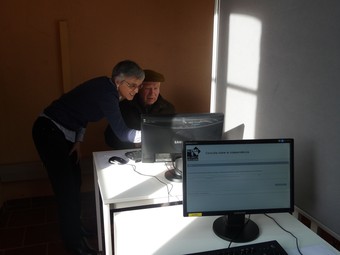 Una voluntària resol un dubte a un votant d'Alella sobre el sistema informàtic per validar el seu  vot T.M
