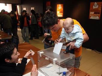 Un votant amb el seu fill en braços diposita ahir la papereta a un dels set centres que es van habilitar a Molins. O. DURAN