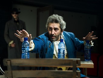 Xavier Ruano (Macbeth) a
			H.I.M. buscant l'equilibri de tres botelles d'aigua, al seu bar perdut. Al fons, arriba Hamlet.  ALBA LAJARIN