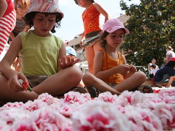 Unes nenes, envoltades de calvells, col·laboraren en l'elaboració d'una catifa.  ROSA IGLESIAS