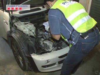 Un agents dels Mossos revisa un dels vehicles sostrets recuperats en un dels taller de la xarxa