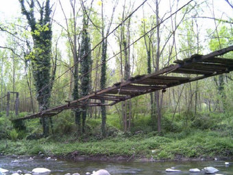 Aquest era l'estat que presentava el pont penjat sobre la riera d'Osor abans de caure l'agost passat. EL PUNT
