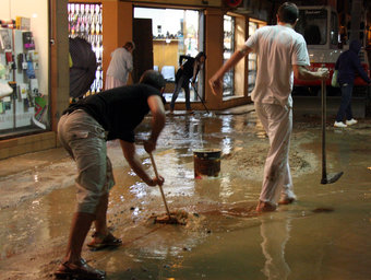 Veïns i comerciants de Calella treuen aigua dels seus portals després de la intensa pluja d'aquest divendres ACN