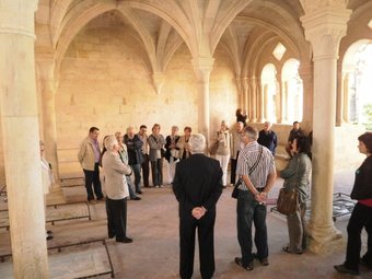 Un grup de visitants escolta, atent, les explicacions que la guia els dóna sobre la vida dels monjos que van habitar el Monestir de Santes Creus J. O