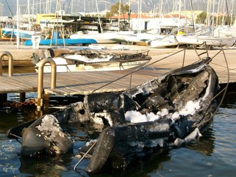 Una de les embarcacions afectades per l'incendi mig afonada al pantalà del port. EL PUNT