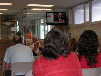 Usuaris d'un hospital català, miren un televisor instal·lat a la sala d'espera MONTSE TURÀ