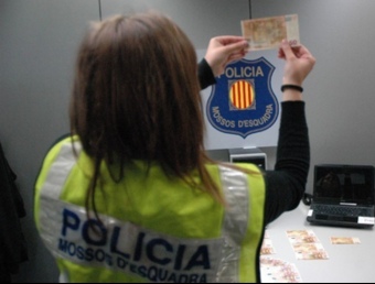 Una Mossa d'Esquadra observa un dels bitllets falsificats que van trobar al detingut EL PUNT