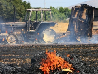 El tractor i la màquina d'embalar, totalment cremats en un camp situat entre el Mas Pere i el Mas Buscà, a Palau-Sator. MANEL LLADÓ