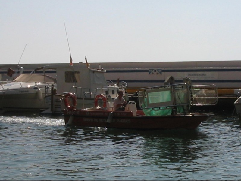 La barca de neteja de propietat municipal actuant al litoral de Lloret de Mar, recollint escombraries. EL PUNT