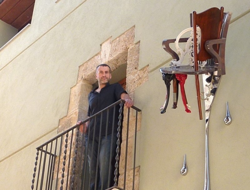 Kel Domènech al balcó de casa seva i l'escultura que fa pocs dies va instal·lar a la façana. R. E