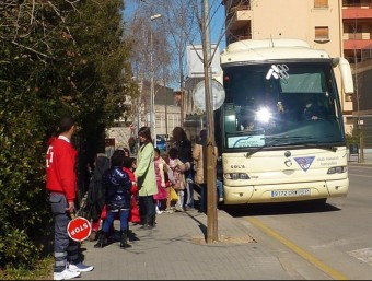 Un autobús escolar del Pla de l'Estany fent una parada davant d'una escola. R. E