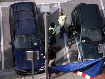 Agents dels mossos buscant indicis entre els dos cotxes on va aparèixer la víctima a Sant Andreu de la Barca ACN