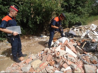Dos mossos inspeccionant ahir una pila de runa llençada enmig d'un camí, al barri de Taialà de Girona G. PLADEVEYA