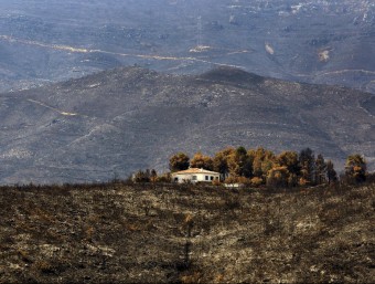 Vista d'una casa vorejada de vegetació cremada EFE