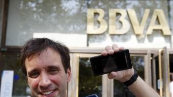 Jordi Abelló, ahir, al davant de la seu del BBVA, a la plaça Catalunya de Barcelona, un dels punts on es pot veure l'exposició al telèfon mòbil. ORIOL DURAN
