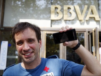 Jordi Abelló, ahir, al davant de la seu del BBVA, a la plaça Catalunya de Barcelona, un dels punts on es pot veure l'exposició al telèfon mòbil. ORIOL DURAN