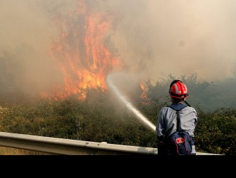 Un efectiu dels bombers lluitant contra l'avenç de les flames, al terme municipal de Sant Joan de Mollet. MANEL LLADÓ