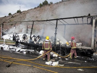 Els efectius dels bombers acabant de remullar les restes del camió, que transportava mobles i bobines de paper MARTÍ ALBESA