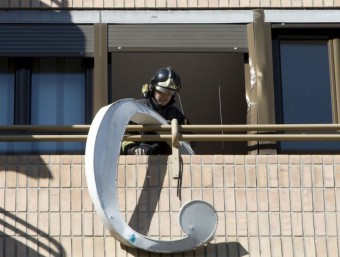 Un bomber treballa a l'edifici afectat pel vent amb la caiguda d'un cartell de grans dimensions. EL PUNT AVUI