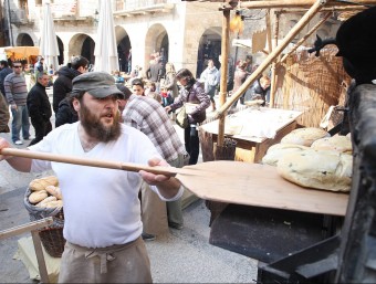 Un flequer enforna el pa cuit amb llenya, en una de les parades més vistoses de la fira medieval de Besalú LLUÍS SERRAT