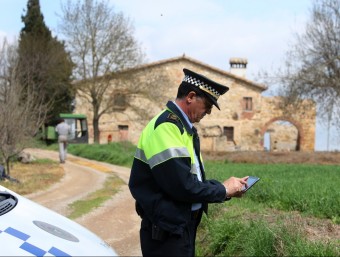 Un agent de la policia municipal de Llagostera amb la tauleta digital, davant d'una de les masies geolocalitzades a l'aplicació LLUÍS SERRAT