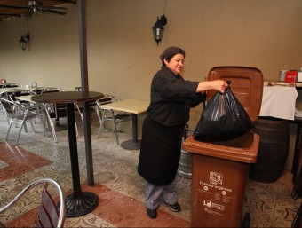 Una dona introduint la fracció orgànica del local al contenidor, a Caldes . LLUÍS SERRAT