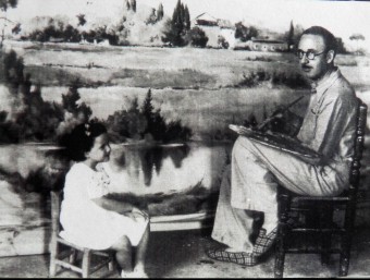 Ramon Reig pintant un dels seus paisatges amb sabatilles d'estar per casa, als anys quaranta, mentre és observat per la seva filla, Maria Blanca Reig FAMÍLIA REIG
