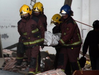Els bombers traslladant el cos de la víctima mortal de l'esfondrament. TÀNIA TÀPIA (ACN)