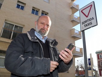 José Franco amb el seu telèfon intel·ligent en una parada de taxis davant l'estació de trens de Mataró.  QUIM PUIG