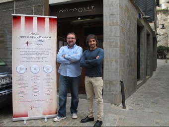 David Illa, propietari del Mimolet, al costat del menú. A la dreta, l'autor de la cançó, Jesús Torrero, tots dos davant del restaurant J.N