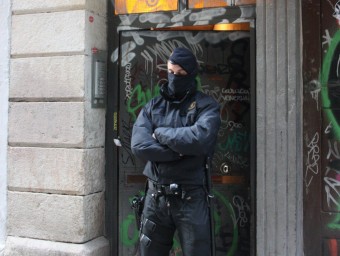 Un agent dels Mossos fa guàrdia davant un dels edificis on s'ha dut a terme un dels escorcolls ACN