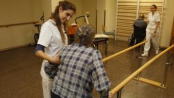 Dues persones grans fent activitats de rehabilitació i manteniment físic en una residència de Barcelona acompanyats de les cuidadores ORIOL DURAN / ARXIU