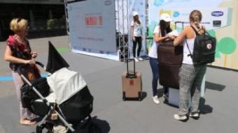 Una noia puja una maleta a la bàscula que Danone va muntar ahir a l'estació de Sants, en la campanya de recapte QUIM PUIG