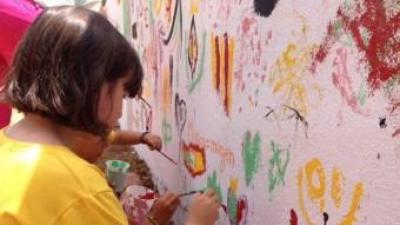 Unes joves participen en la pintada del mural de la Trobada. ESCOLA VALENCIANA