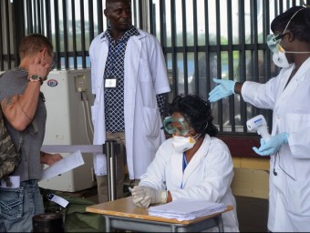 Un equip sanitari revisant l'equipatge d'un viatger que marxava ahir de l'aeroport de Liberia, encara obert als vols REUTER