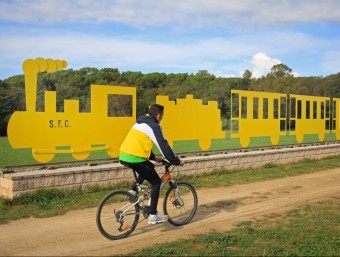 Un ciclista passant per davant el monument del carrilet, que des de fa uns dies està pintat totalment de groc. LLUÍS SERRAT