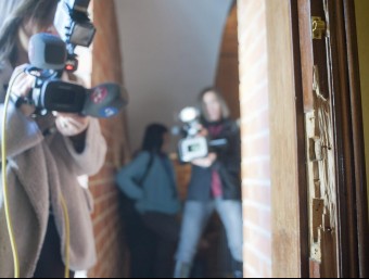 Un càmera filma la porta esbotzada del pis on viu el jove detingut a Sant Feliu de Guíxols, aquest dimarts EFE