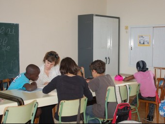 Una voluntària ajudant a estudiar un grup d'alumnes dels serveis educatius de Càritas del Pla de l'Estany. EL PUNT AVUI